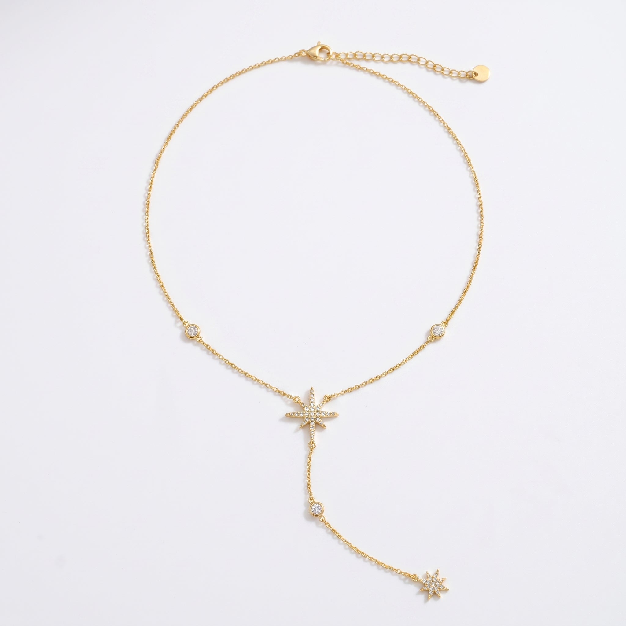 A delicate gold Y-shaped necklace featuring three starburst charms and small round pearl-like beads, displayed on a clean white background.